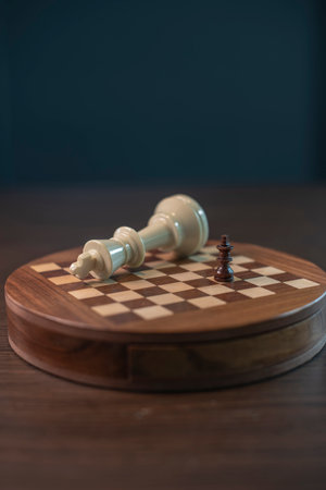 An abstract chess game with a little black king checkmates a big white king on the wooden chess...