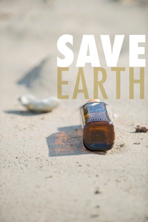 Save Earth awareness on the Earth day. Empty brown clear bottle with cap left on the beach. A starting point of the environment problem.の写真素材