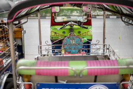 Well known and famous local taxi in Thailand, Tuk-Tuk, parking nearby tourist place, waiting for passengers asking for a ride. Image showing lots of details of colourful equipments and elements.の写真素材