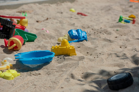 Colourful plastic toys with various shapes and kinds left unattended on a sand box in a resort, waiting for kids to come and enjoy them in a morning.の写真素材