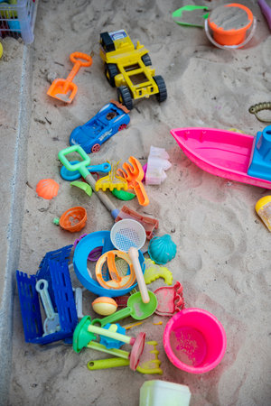 Colourful plastic toys with various shapes and kinds left unattended on a sand box in a resort, waiting for kids to come and enjoy them in a morning.の写真素材