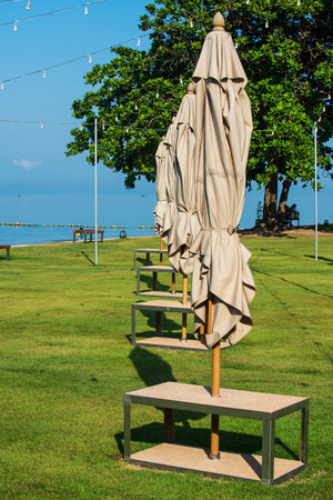 Outdoor seating set with unfold umbrellas on the grass near the beach of the modern resort in the morning time.の写真素材