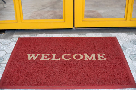 Welcome red mat greeting all visitors in front of a yellow glass door for  shop and restaurant in a shopping mall.の写真素材