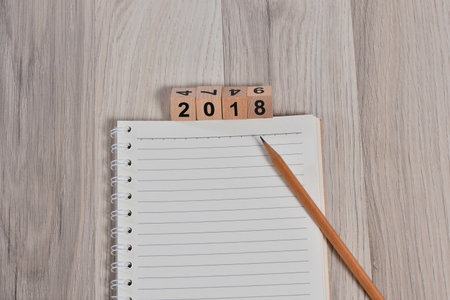 White line paper with 2018 new year cubes on brown wooden background, top viewの写真素材