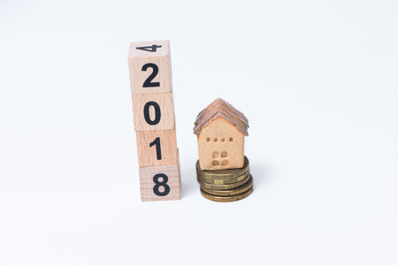 The wooden cube for new year with the house model and coins on white backgroundの写真素材