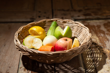 mixed fruit in wood basket on wood table in morning light front viewの写真素材