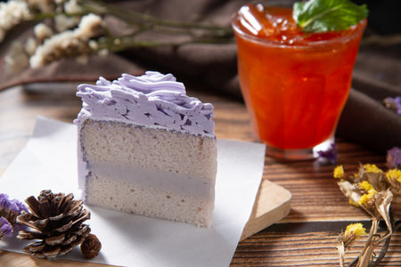slice purple taro cake on rectangle white paper and wooden plate with ice mint tea lay on wood table...