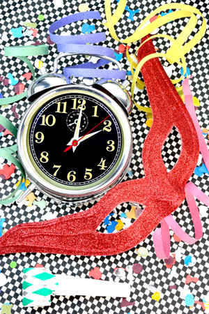 Carnival concept with an alarm clock, mask , confetti, serpentines on chessboard background