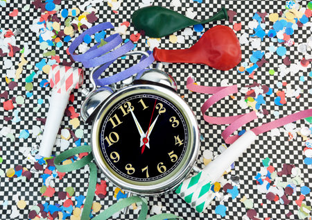 Party time concept  with an alarm clock, streamers , balloons and noisemakers on chessboard backgroundの写真素材
