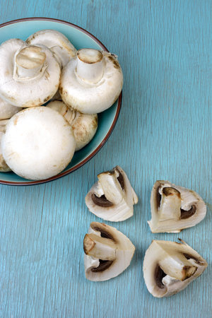Agaricus bisporus mushrooms in bowl  on turquoise blue tableの写真素材