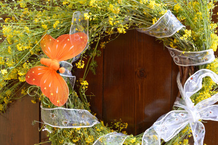 Wreath of yellow wild flowers and decorated with an orange butterfly on wooden backgroundの写真素材