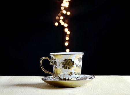 Coffee cup on matte wooden surface and  sparkling light dots on backgroundの写真素材