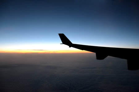 Silhouette of airplane wing while is on flight on sunrise time