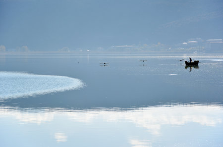 Fisherman and pelicans in the lakeの写真素材
