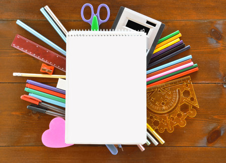 Blank spiral-bound notebook and school supplies on wooden  table