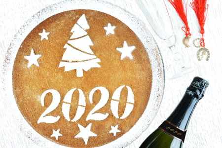 Greek new yearâ€™s cake, vasilopita,a bottle of champagne,a class and lucky charms with red...