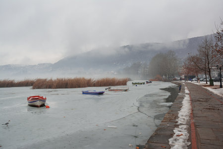 Pedestrian alley on the banks of frozen lake Orestiada in Kastoria of Greece on a cloudy dayの写真素材
