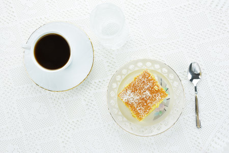 Greek ravani cake with a cup of black coffee on lace matの写真素材