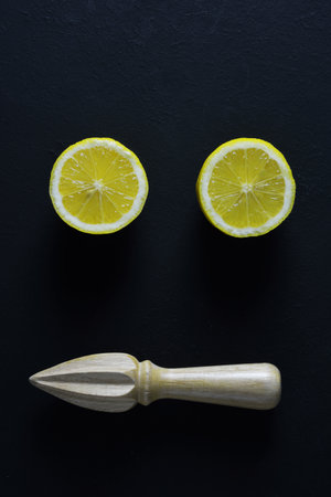 Halves of lemons andÂ  wooden squeezer on black backgroundの写真素材