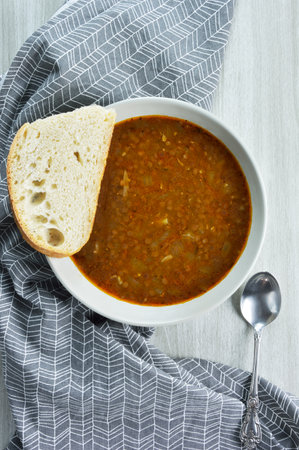 Slice of bread on plate with lentil soup and a spoon on kitchen towelの写真素材
