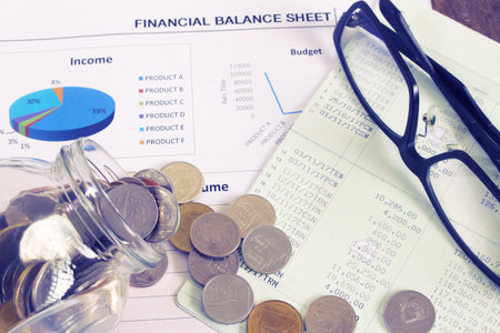Coin and book bank account and glasses on report document.の写真素材
