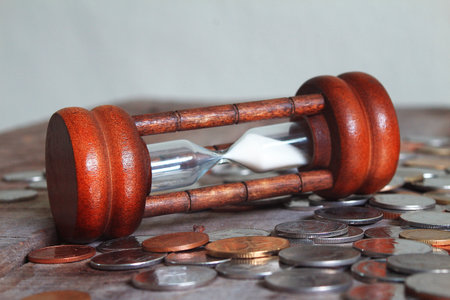 Hourglass and coins on wood plate , financial concept の写真素材