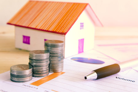Stack of money and pen on paper report and background house model. の写真素材