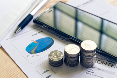 Stack of money and pen on paper document with smart phone on background の写真素材