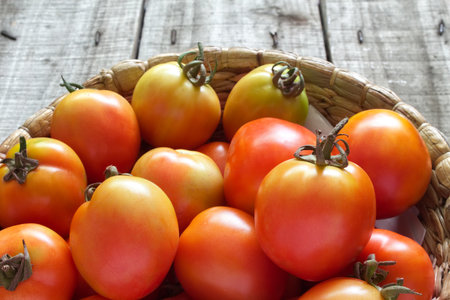 Close up harvest tomatoes keep in basket on old wood floor.の写真素材