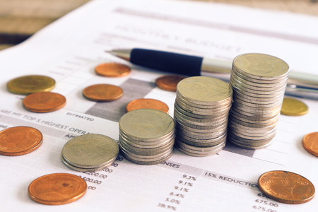Close up pen and compass and coin stack on income document , finance concept.
