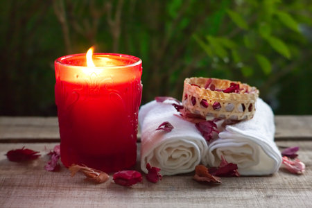 Red aroma candle and towel decorate with dry rose on wood table , spa concept.の写真素材