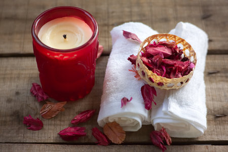 Red aroma candle and towel decorate with dry rose on wood table , spa concept.の写真素材
