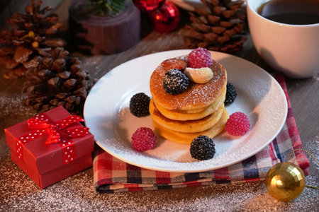 Pancake topping with berries and nut with background gift and pine cone under christmas tree, holiday party dessert.の写真素材