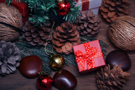 Red gift boxes and gold and red balls and pine cones decorate under christmas tree.の写真素材