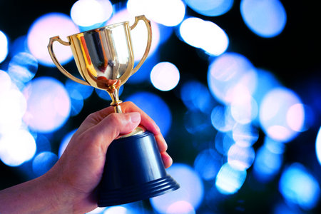Winner hold trophy with abstract bokeh on dark blue backgroundの写真素材