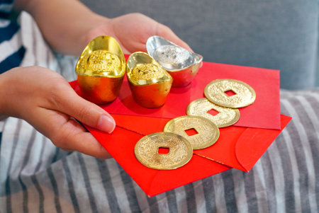 Hands hold red envelope which have gold coin and gold bar for chinese new year concept