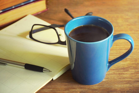 Blue coffee cup with planning book and pen on tableの写真素材