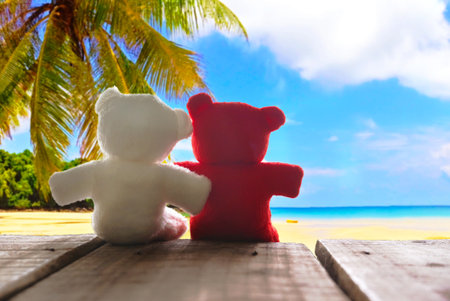 Red and white teddy bears sit on wood plate with background seascapeの写真素材