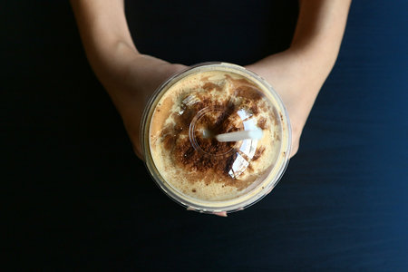 Topview a cup of coffee frappe blending with ice on two handsの写真素材