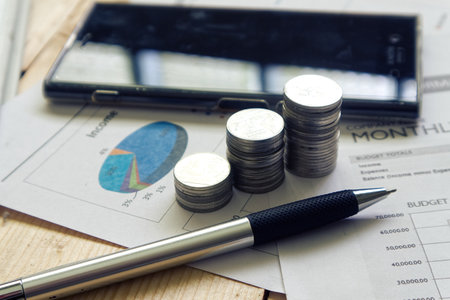 Stack of money and pen on paper document with smart phone on backgroundの写真素材