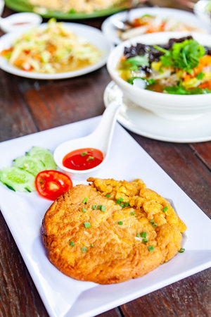 Pork Omelet and Sauce on White Plate with Som Tam and Many Food on Wood Tableの写真素材