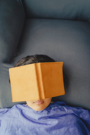 Young Asian Woman Relaxing and Fall Asleep While Reading Book on Sofa in Living Room, Close Up Shot.の写真素材