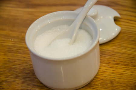sugar in cup and spoon on tableの写真素材