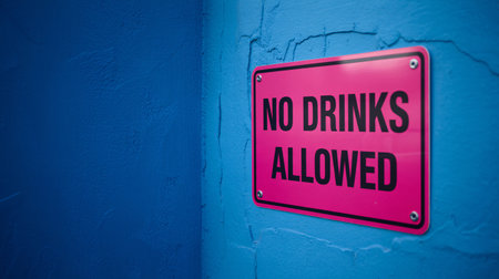A pink sign with the words NO DRINKS ALLOWED is mounted on a textured blue wall, creating a stark contrast.の素材