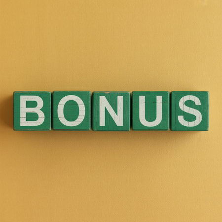 Top down view of the word BONUS created with green wooden letter blocks. The white letters stand out against the green cubes on a solid yellow background, representing rewards and incentives.の素材