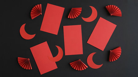 A flat lay of red paper cutouts, including envelopes and crescent moons, arranged on a black surface, evoking a festive Chinese New Year theme.の素材