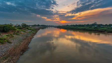 Beautiful colors and reflections as the sun sets over the trees on a calm lake.の写真素材
