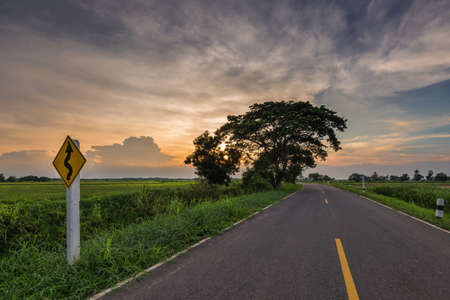 sunset in clouds with sunrays over road to horizonの写真素材