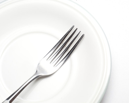 White plate, fork  on light background 