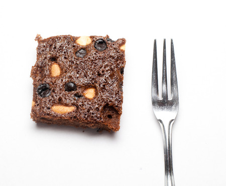 Piece of brownie with fork and knife on white isolated background の写真素材